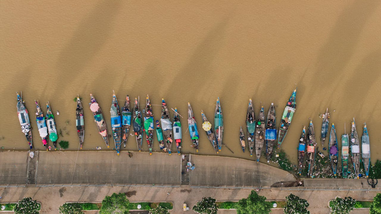 who-we-are An aerial view of colorful boats moored along the riverbank of Phnom Penh, Cambodia.
