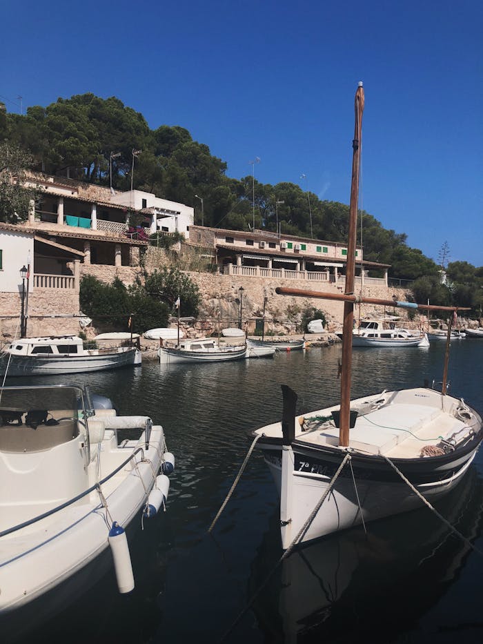 our-story Scenic view of boats in a serene harbor at Santanyí, Mallorca on a clear day.
