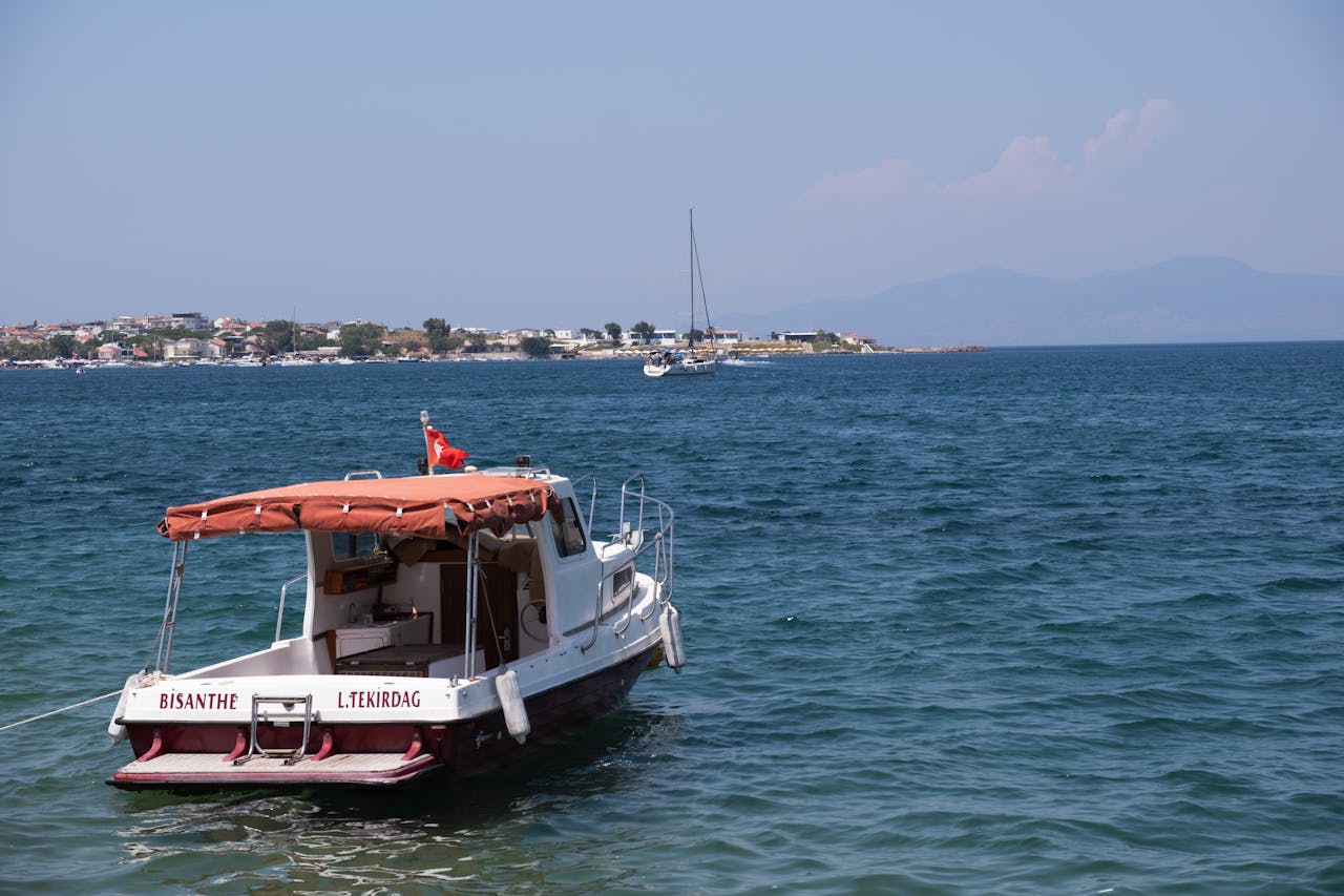 about-us A picturesque view of a boat anchored in the calm waters of Foça, İzmir, Türkiye.